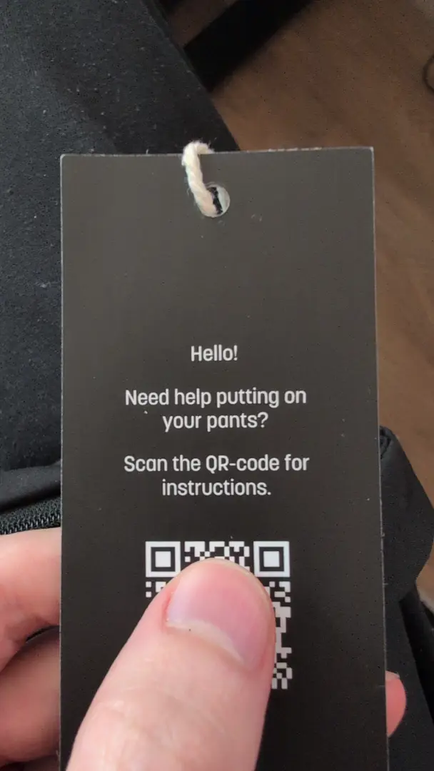 A clothing label with the following text:

Hello!
Need help putting on your pants?
Scan the QR-code for instructions.